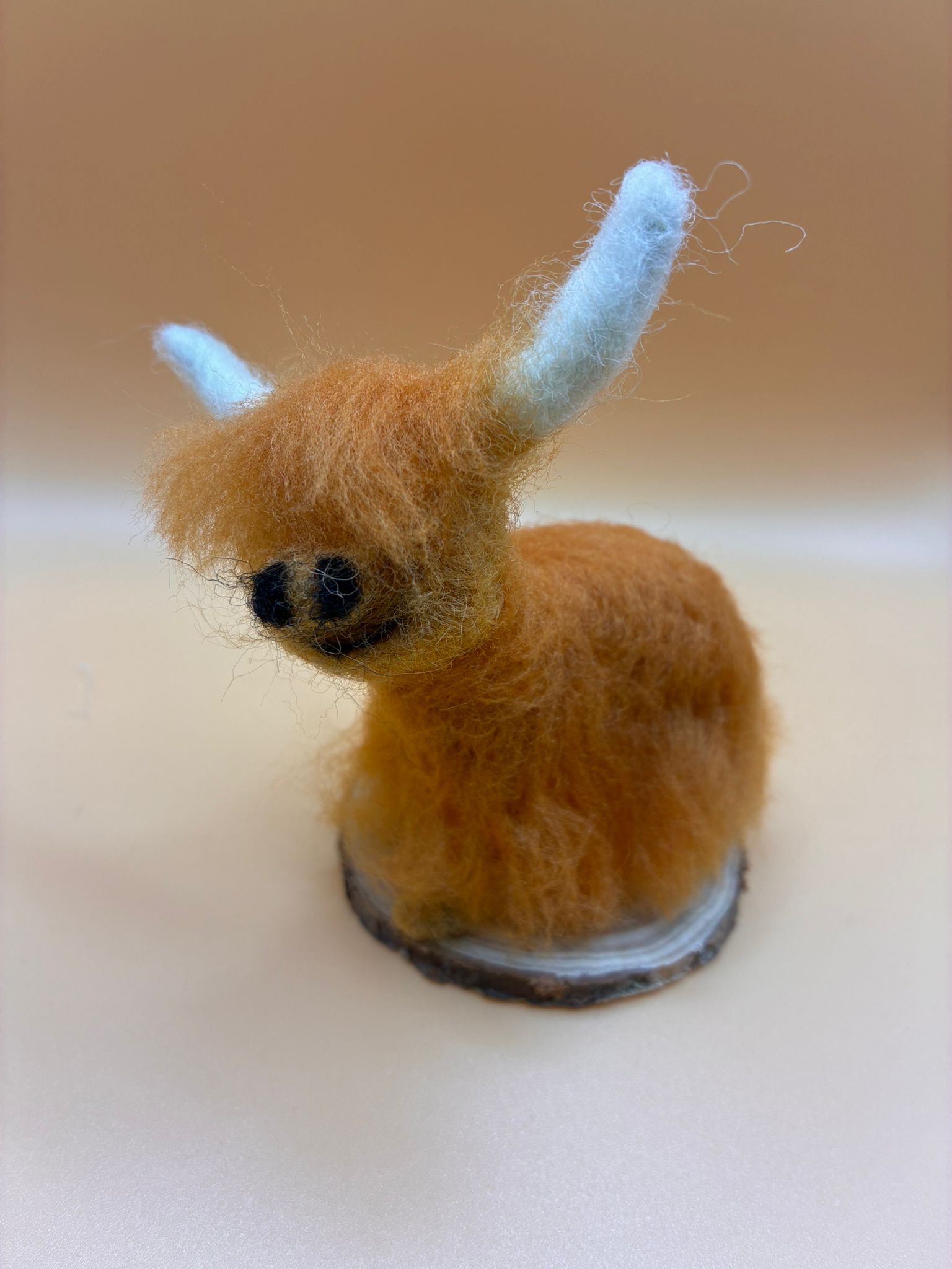Needle felt small highland cow on wood slice