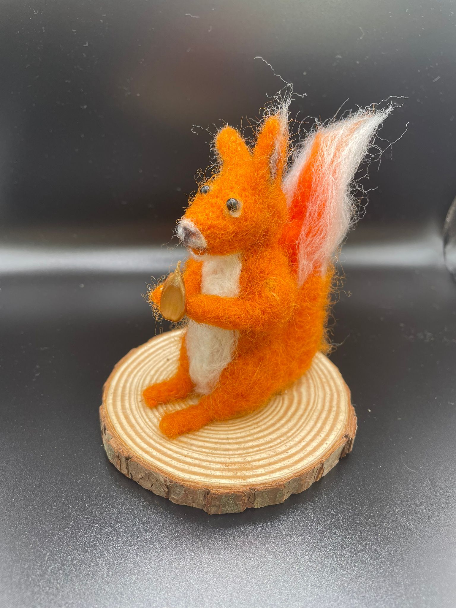 Needle felt red squirrel with acorn on wood slice